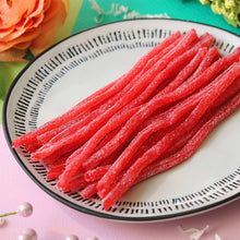 Strawberry Sour Punch straws on a plate, red sugar-coated candy sticks
