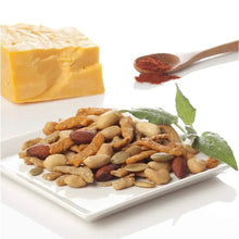 Assorted nut mix on a plate with cheese cubes and a pinch of spice on a spoon.