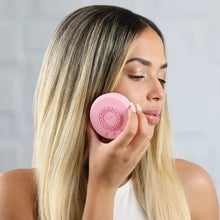 Pink circular skincare infuser held to a woman’s cheek