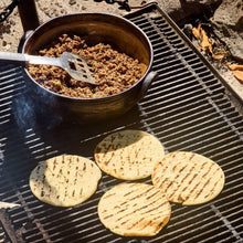 Grilled tortillas on a barbecue grate over taco seasoning filling