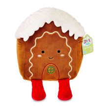 Plush gingerbread house baby toy with brown body, white roof, smiling face, red feet