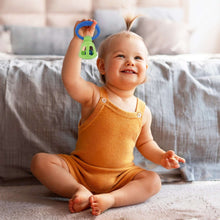 Lime green and blue bell rattle toy with handle ring shown in use