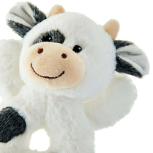 Plush cow rattle close-up face with tan muzzle, black eyes, smile and striped ears
