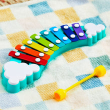 Rainbow xylophone bars on cloth blanket with yellow mallet and white cloud ends