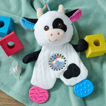 Cow teether plush with patterned belly window, rainbow horn, and textured pink and blue feet