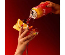 Red sparkling water mocktail can pouring into a stem glass with orange slice garnish