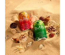 Sparkling water mocktail cans on sand with seashells and starfish, three flavors
