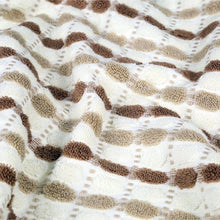 Tan bath towel with brown dotted grid pattern, visible terry loops and textured weave