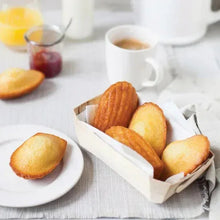 Madeleine sponge cakes in paper tray with coffee cup and two loose cakes