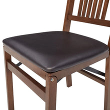 Wood folding chair with dark gray padded seat and slatted back, close-up