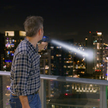 Handheld blue tactical flashlight projecting a wide beam