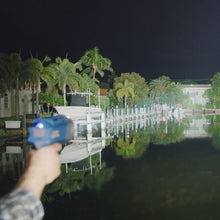 Handheld blue tactical flashlight shining a beam at night
