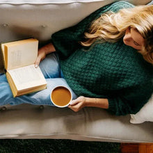 Coffee mug held on couch beside Starbucks Holiday Blend K-Cup pod box