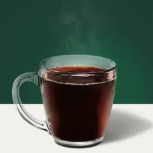 Glass mug filled with dark coffee, clear handle, on light surface
