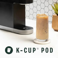 K-Cup brewer with pod area and vanilla iced coffee in a clear glass cup