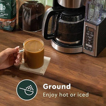 Starbucks Morning Joe ground coffee cup beside coffee maker on wooden countertop