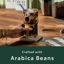 Glass iced coffee with coffee grounds on a base, with Starbucks ground coffee bag