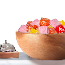 Starburst Original chewy candy in a wooden bowl, mixed pink, red, and yellow wrapped pieces