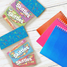 Assorted Starburst and Skittles chewy candy single packs arranged on a flat surface.