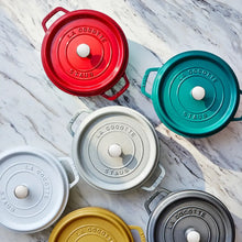 Round Dutch oven lids in red, teal, white, gray, and dark colors, laid out flat