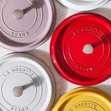Round Dutch oven lids close-up in mauve, red, white, and yellow with metal knobs