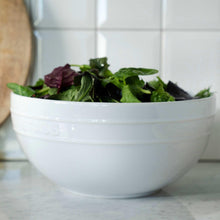 White Staub ceramic serving bowl filled with mixed greens