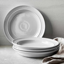 Staub white dinnerware set showing stacked plates with embossed logo