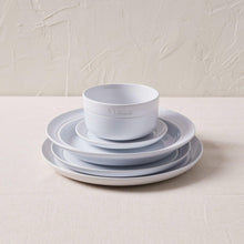 Staub white dinnerware set with stacked bowls and plates, round forms