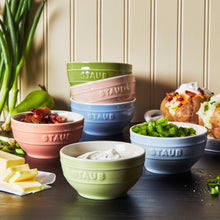 Pastel ceramic mini bowls and lidded mini Dutch ovens arranged on countertop