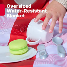 Red and white striped blanket with toy plates, cups, and dessert-style food pieces.