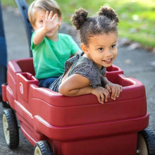 Red kids ride-on wagon with seat area and belt-style safety straps, shown in use