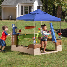Children using outdoor water activity center with blue canopy, slide and splash pump