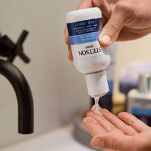 Hand squeezing cooling shave oil from bottle nozzle into palm