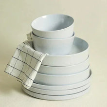 Celina dinnerware set stack with light gray bowls and plates; includes cloth napkin