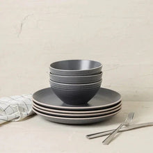 Gray speckled stoneware dinnerware set with bowls stacked on dinner plate