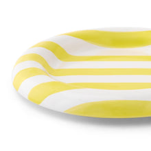 Round white appetizer plate with yellow and green wavy stripes