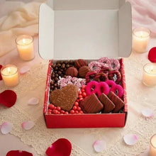 Valentine chocolate gift box open, filled with heart chocolate, round candies, pink frosted treats