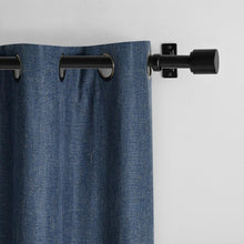 Blue blackout curtain panel with grommet rings on a black curtain rod