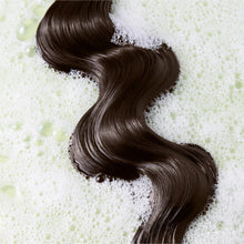 Wavy dark brown hair strands with bubbles and foam, soft and glossy look