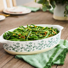 Oval ceramic baker dish with green herb-pattern sides, filled with green beans