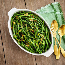 Oval ceramic baker dish with green herb-pattern sides, filled with sautéed green beans