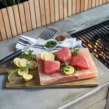Himalayan salt block with thick steaks, herbs, and lemon slices on board