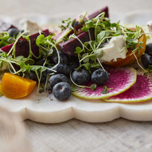 White marble platter with scalloped rim holding salad, blueberries, and citrus