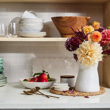 White marble platter with scalloped edges on countertop with plated food