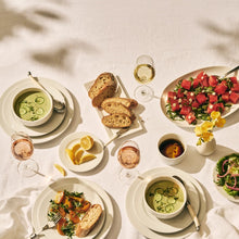 Set of off-white round salad plates arranged for a meal on a table.