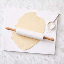 Marble rolling pin with wooden handles on a pastry board