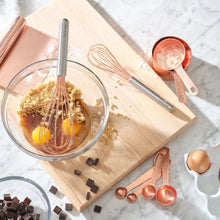 Copper measuring cups with handles, nested near a small copper spoon