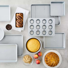 Assorted metal bakeware pieces: muffin pan, round cake pan, baking sheets, and loaf pan