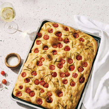 Rectangular baking tray holding baked cookies with red toppings and herb sprigs