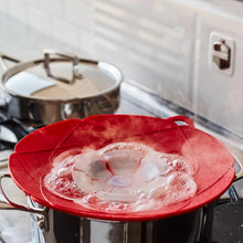 Red spill stopper lid with fan vent over pot rim, with bubbles visible